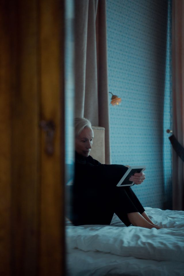 Mulher sentada na cama, acordada, num quarto escuro de madrugada